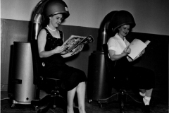 Two women under salon-grade Penguin hair dryers