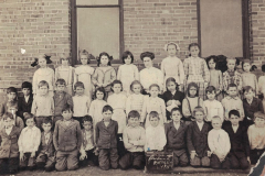 Photograph, First Grade 1911, Garland School Photo of Garland School 1st grade class in 1911.  Bottom row, left to right:  4 Jack Sanders, 5_______ Talley, 6 Harvey Sanders, 7 Raymond Hamilton, 8 Cyril Flook, 9 ________ Willeford, 12 Robert Crossman, 14 Tommy Moss; 2nd row:  Alton Hamilton, 4 ________ White, 5 Mattie Pickett, 6 Mary Lizzie Bell, 7 Nela Weaver, 11 "Deacon" Green.  3rd row:  Lera Pendleton, 2 Hazel Rountree, 3 Betty McCallum, 5 Lola Morrison, 8 Florrie Allen, teacher, 11 Nell Brown, 12 Ruth Halsell, 13 Bennie White.