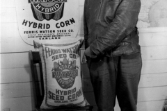 John Stern from Iowa, pointing to sack of seed corn. Mr. John Stern from Iowa points to a sack of Ferris Watson Texas Hybrid Seed Corn. circa 1930s.
