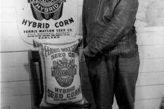 John Stern from Iowa, pointing to sack of seed corn. Mr. John Stern from Iowa points to a sack of Ferris Watson Texas Hybrid Seed Corn. circa 1930s.
