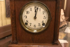 Sessions Mantle Clock Mantle Clock, Garland Post Office d.1924  While WM. J. Williams was a clerk at the Garland Post Office, this clock, made by The Sessions Clock Company based in Connecticut, was found during remodeling. Williams felt a special connection to the clock, since both his grandmother, Nora Seawright Lemmon, and aunt, Grace Lemmon Hartman, were postmasters in the 1910s. Female postmasters have been a common occurrence since the days when the American colonies were still a part of England. In the aftermath of the Civil War, the number of female postmasters in the South rose when men who had pledged allegiance to the Confederacy could not take the oath to become postmaster. The clock has pencil markings, such as SP and C, which would have been used in retail at the time to signify cost.  Although the Williams family believed the clock may have been acquired by Nora Seawright Lemmon, writing on the back which reads ‘SP 10-5-24 C’ indicates the post office acquired the clock in 1924, when Curtis D. Crossman was postmaster.