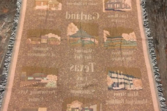 A cotton, woven Garland blanket eith green border and fringe depicting local landmarks.