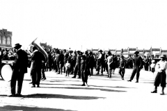 Crowd at Dollar Day on square. Men on the right side of the image can be seen playing instruments.
