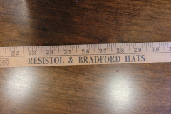 4'-long wooden ruler printed with "Byer-Rolnick Corp.    A KORACORP Company    Resistol & Bradford Hats  'Men of the West Rely on the Best ' 'The Measure of a Man'". The 'Men of the West ' and 'The Measure of a Man' are the slogans of Resistol and Bradford Hats, respectively. Dated based on the year Koracorp acquired Byer-Rolnick.