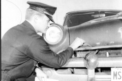 Police officer investigating wrecked car (Name of policeman unknown)