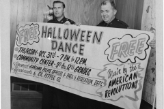 Police officers holding up sign for free Halloween Dance Thursday Oct. 31