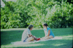 A man and a woman picnicking on a blanket im the park, 1977