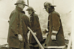 Fire fighters at burning structure, unknown location