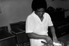 A man standing in a kitchen preparing meat.